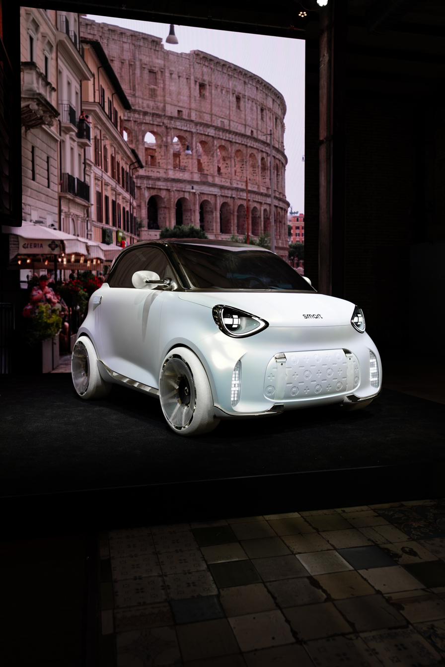 smart Concept #2 blanc perle devant un écran représentant une rue de Rome
